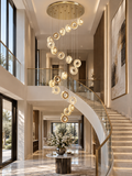 Gold Crystal Spiral Chandelier for Staircase Foyer with warm ring pendants beside a curved staircase