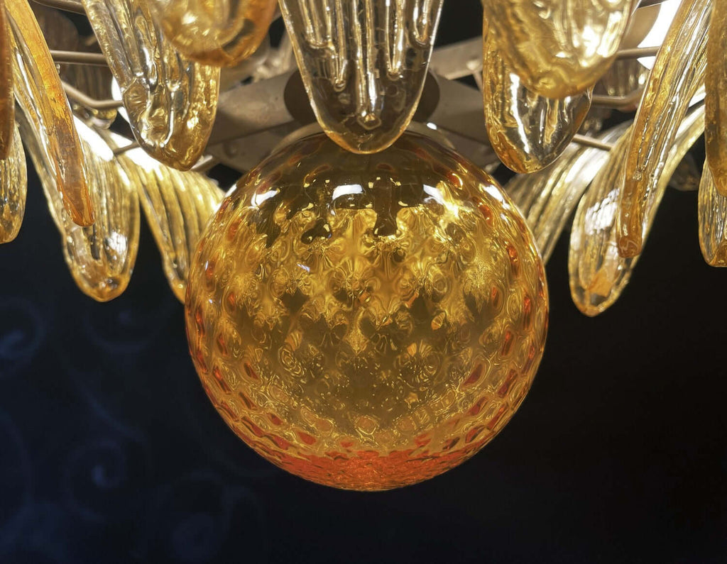 Close-up of the amber glass globe and surrounding leaf shades on the chandelier.