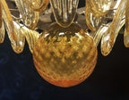Close-up of the amber glass globe and surrounding leaf shades on the chandelier.