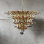 Amber glass Palmette chandelier shown in a large tiered studio view on a gray wall.
