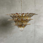 Amber glass Palmette chandelier shown in a wider studio view on a gray wall.