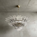 Clear glass Palmette chandelier shown in a compact studio view on a gray wall.