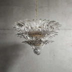 Clear glass Palmette chandelier shown in a wider studio view on a gray wall.