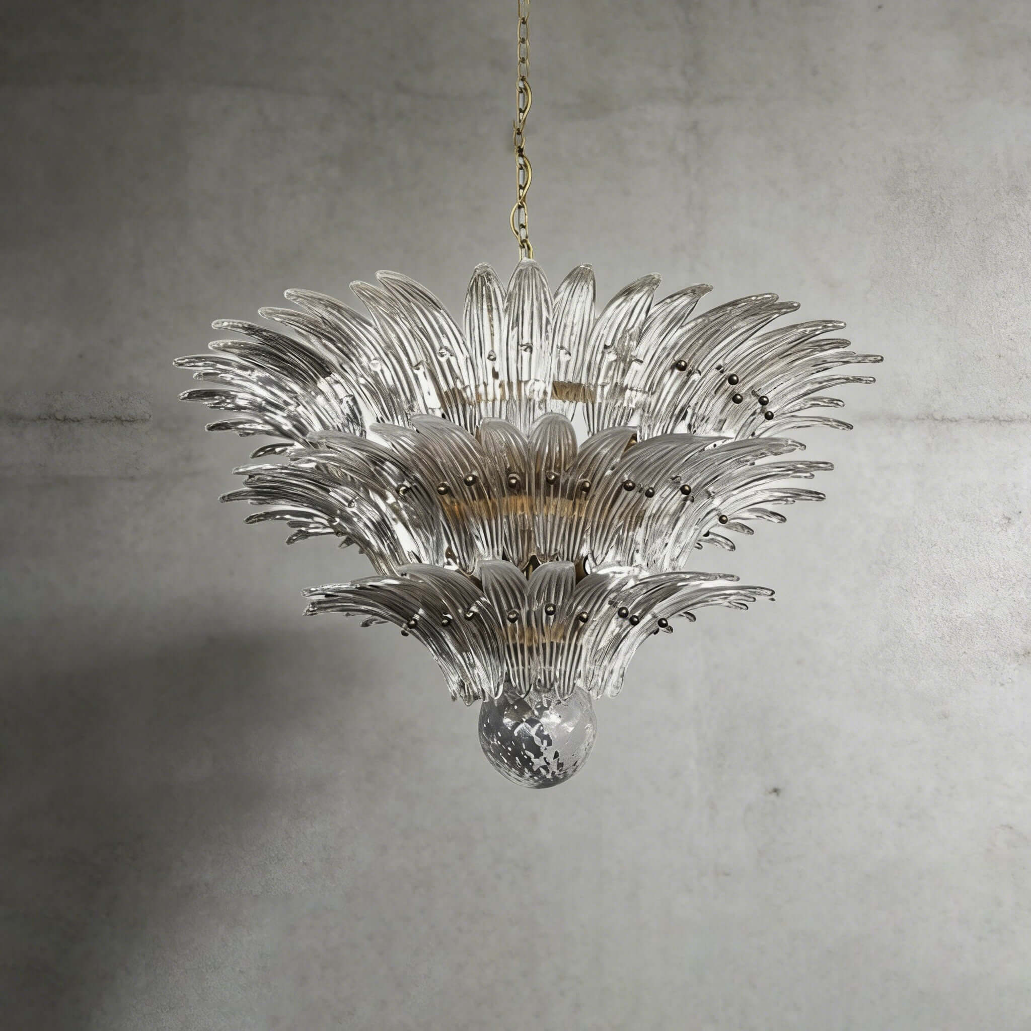 Clear glass Palmette chandelier shown in a wider studio view on a gray wall.
