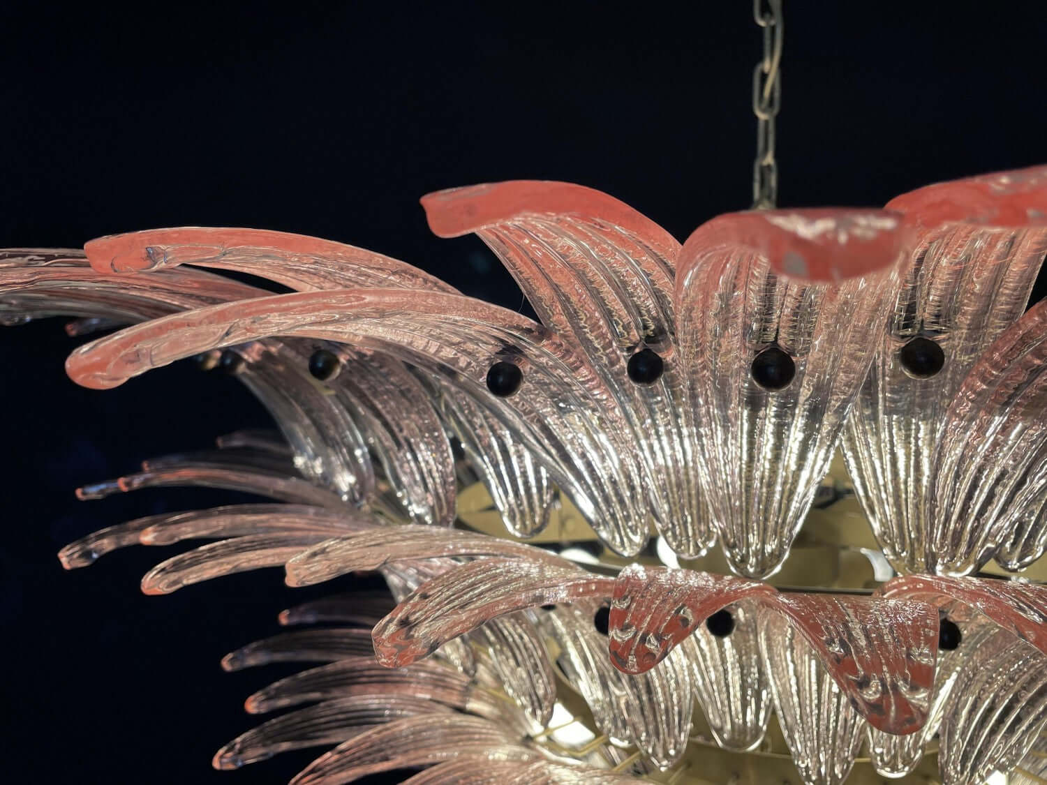 Close-up of pink glass leaf edges and clear glass layers on the chandelier.