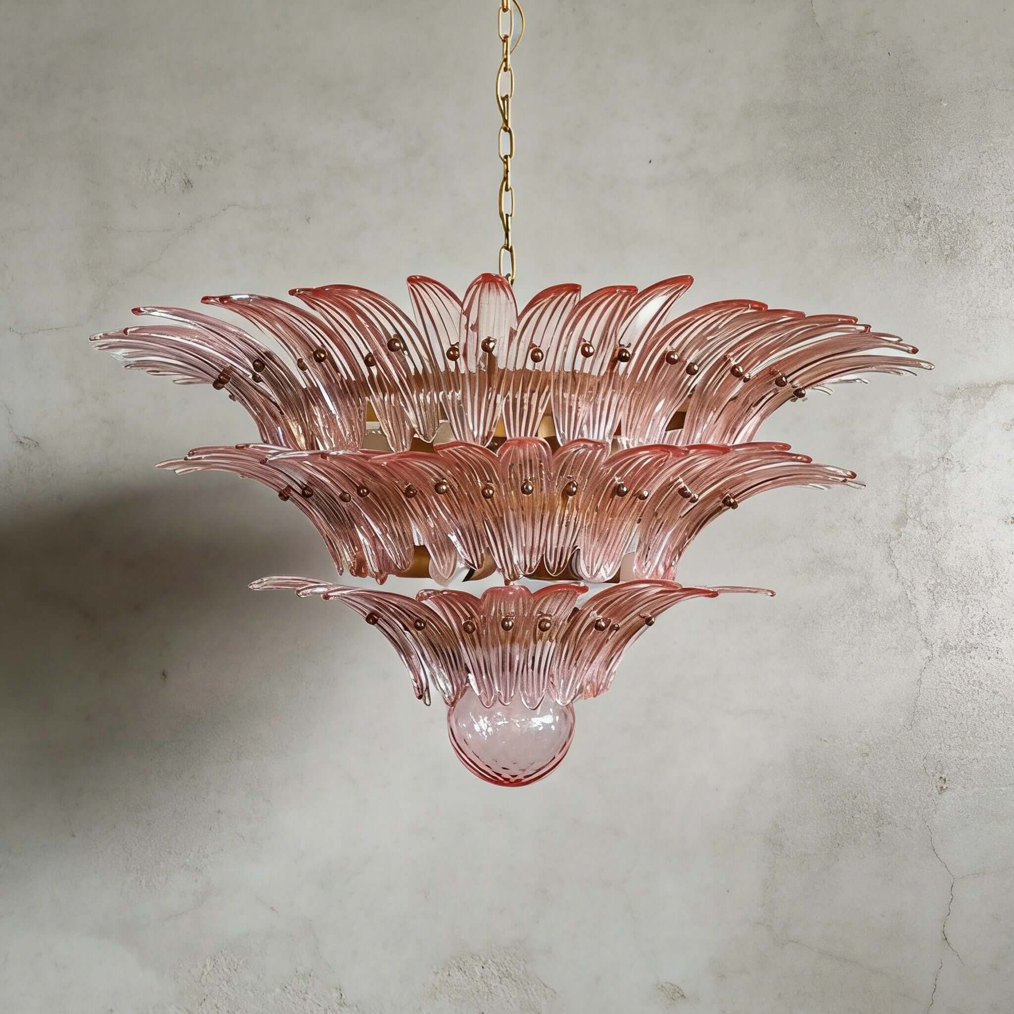 Pink glass Palmette chandelier shown in a wider studio view on a gray wall.