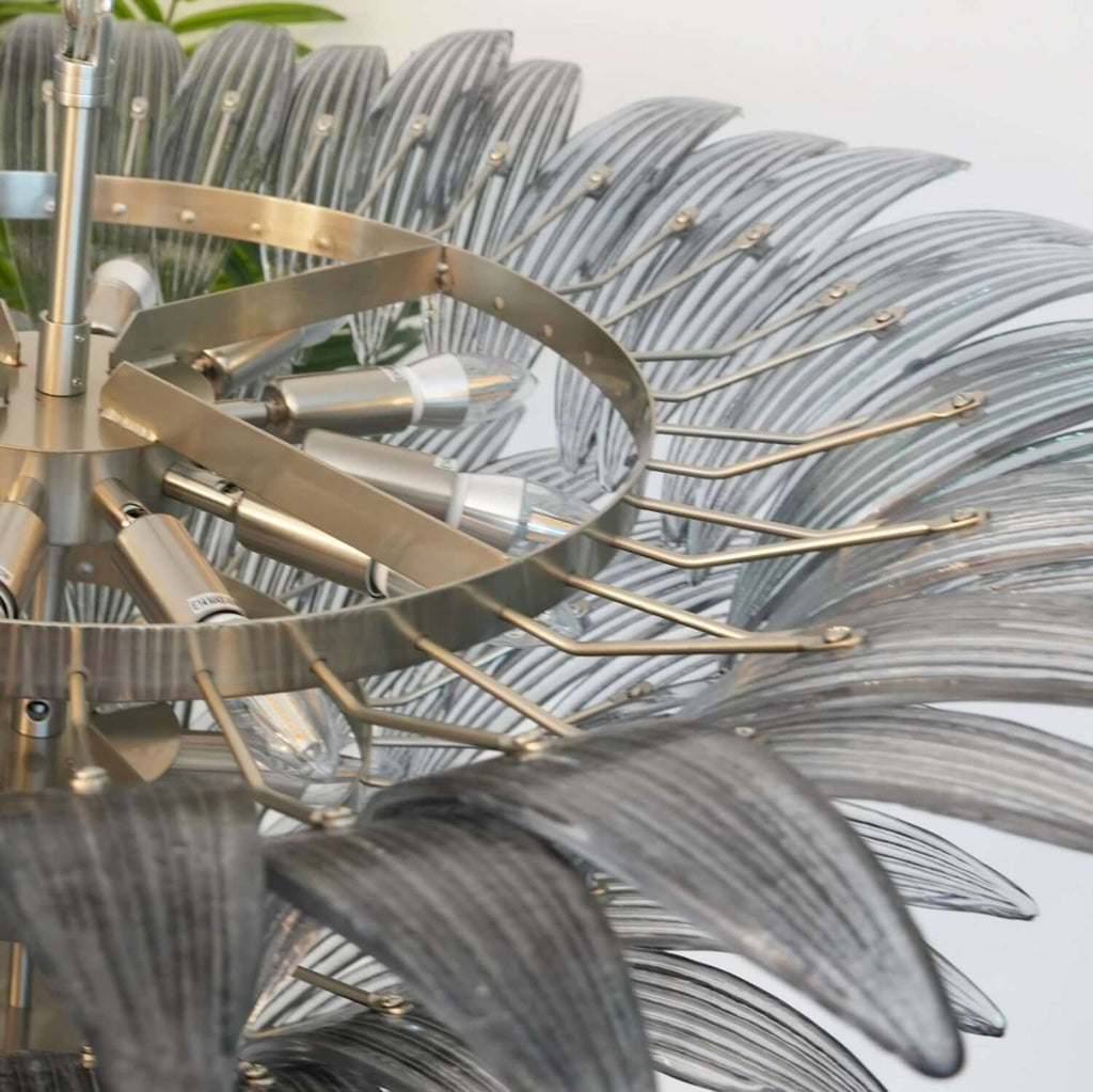 Close-up of the polished metal frame and layered glass leaves on the chandelier.
