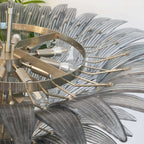 Close-up of the polished metal frame and layered glass leaves on the chandelier.