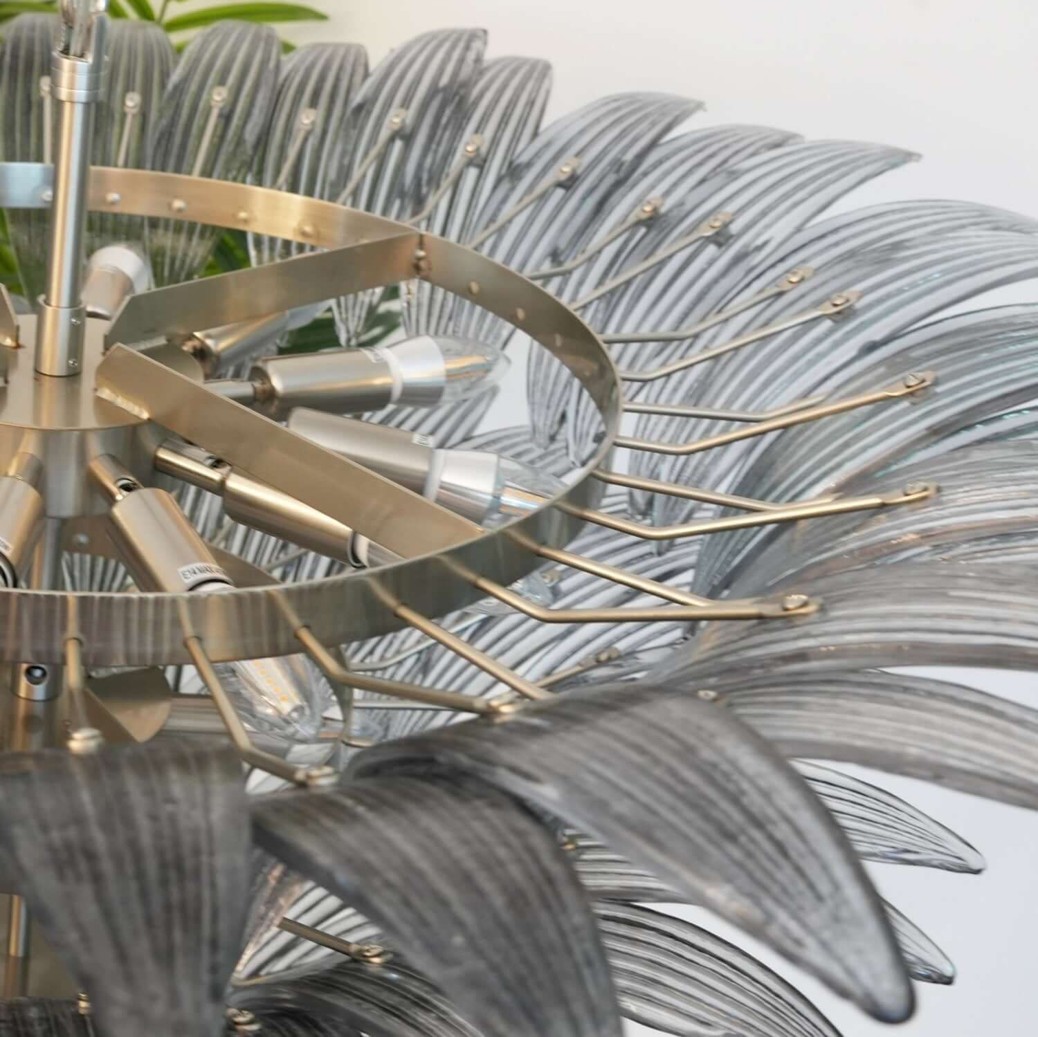 Close-up of the polished metal frame and layered glass leaves on the chandelier.